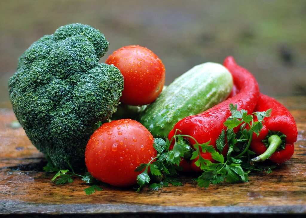 Brocoli, tomates, poivrons rouges, et autres légumes frais sur une table en bois mouillée.