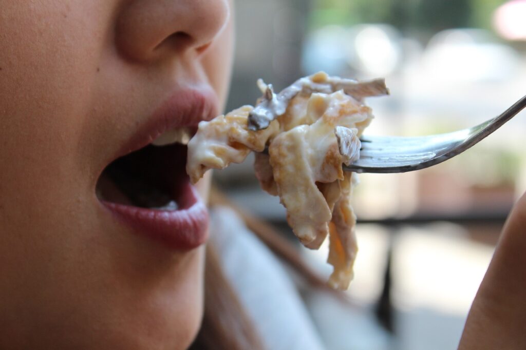 Femme mangeant sa bouchée de nourriture avec une fourchette, illustrant le processus de mastication.