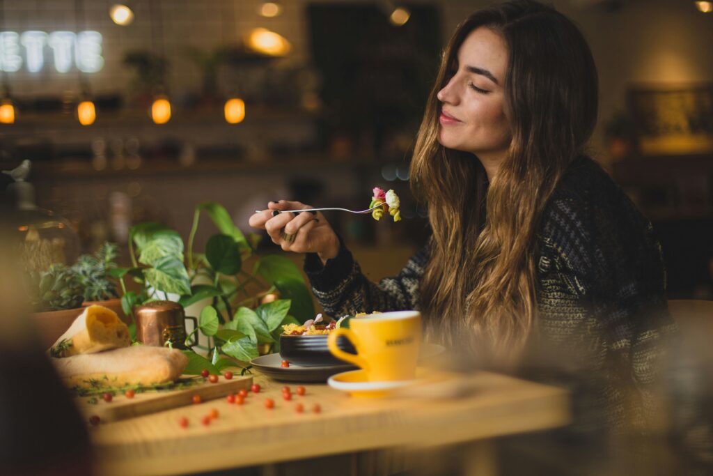 Femme souriante à table, montrant une expérience de repas agréable et paisible.