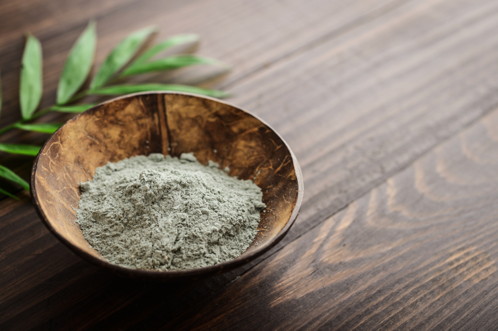 Poudre d'argile verte naturelle dans un bol en bois.