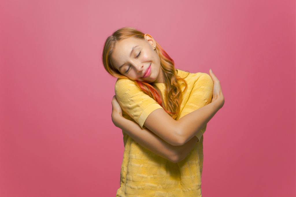 Jeune femme se serrant dans les bras, symbole de la confiance en soi.