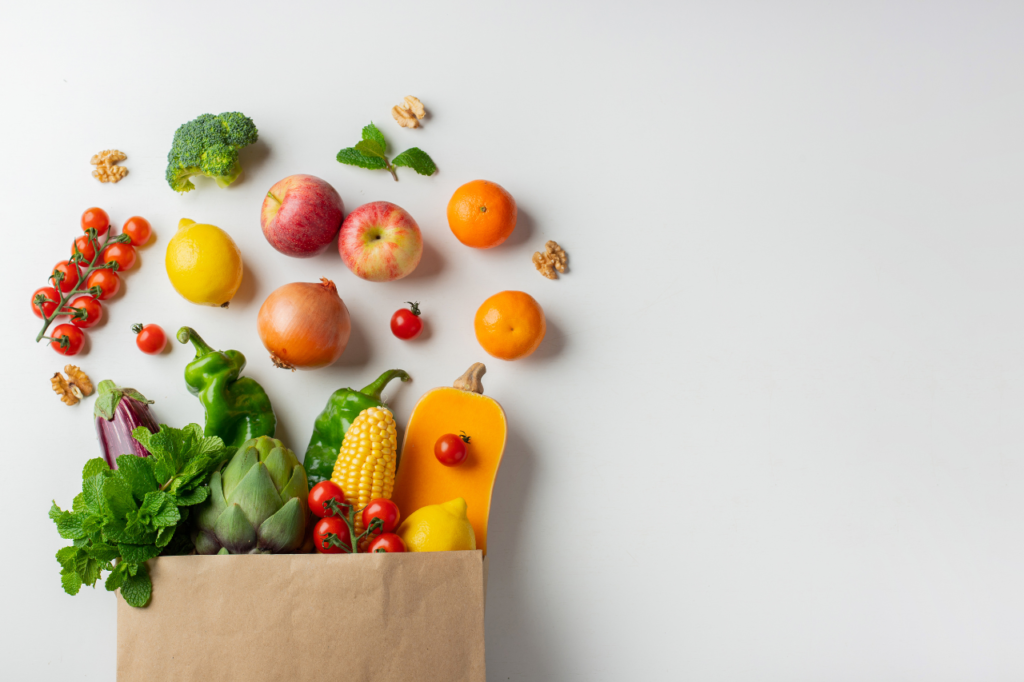 Sac avec légumes et fruits frais, comprenant poivrons, tomates, brocoli, pommes et noix.