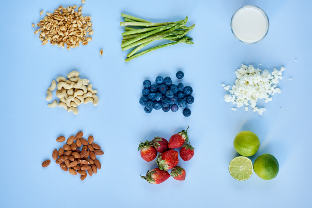 Divers aliments sur fond bleu, incluant noix, asperges, baies et fromage pour des associations alimentaires équilibrées.